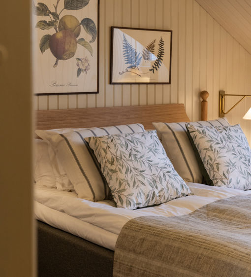 Bäddad säng med vackra prydnadskuddar i herrgårdsstil